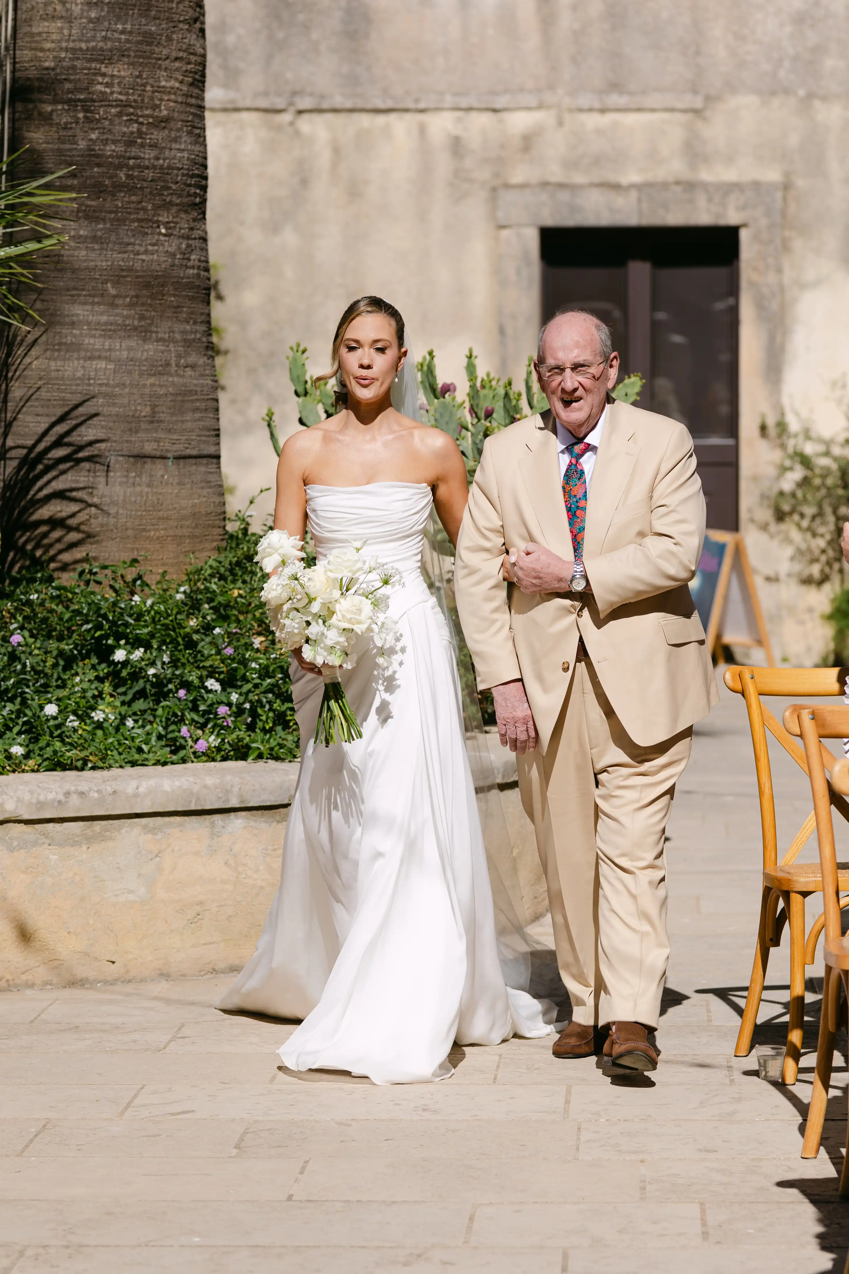 Bride entering luxury Sicilian wedding ceremony with white floral decorations